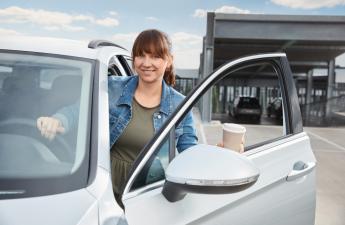 Frau steigt lächelnd aus Auto aus