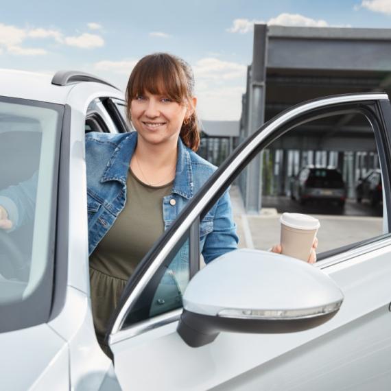 A woman gets out of the car with a smile