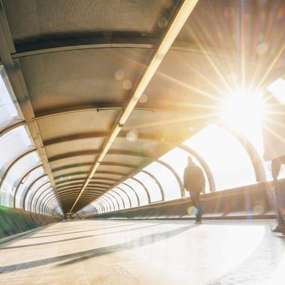 Sonne scheint, Überdachte Brücke mit Fenstern wodurch die Sonne scheint, Menschen gehen 