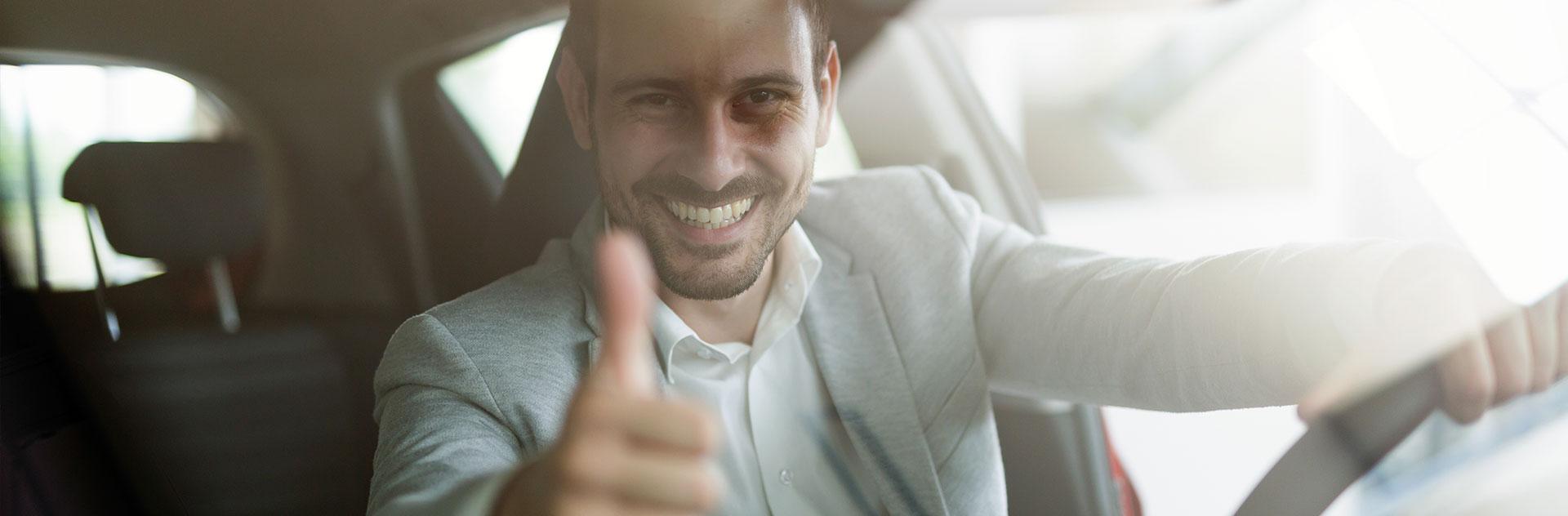 Man sits in the car and shows thumbs up